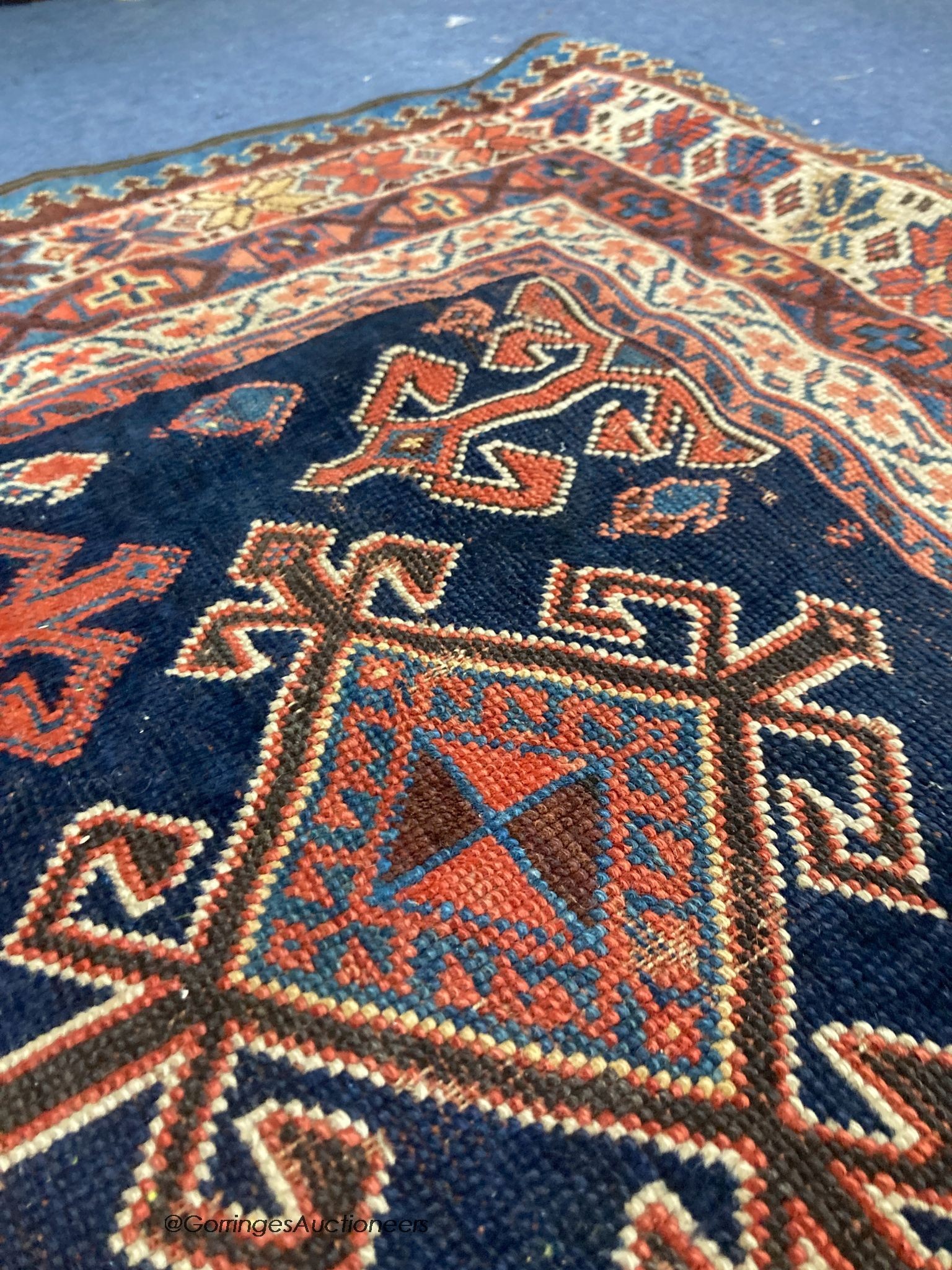 A Caucasian blue ground rug, woven with hooked lozenges, 288 x 152cm